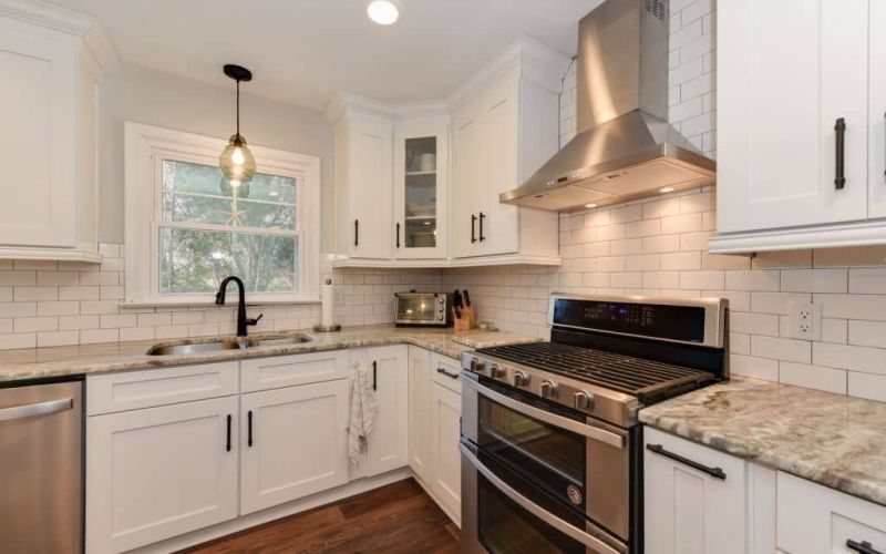 stainless steel appliances in white kitchen with brown wood floors