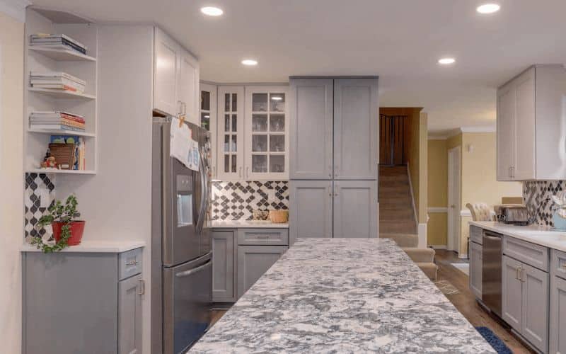 Kitchen with gray cabinets and a corner shelf for cookbooks. 